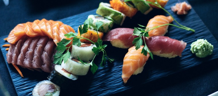 Sushi and sashimi beautifully arranged on a black serving board